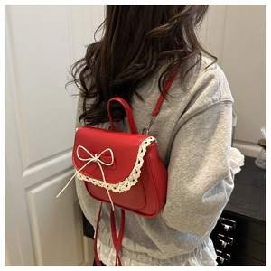 Close-up of red PU leather mini backpack with delicate white lace trim and bow detail