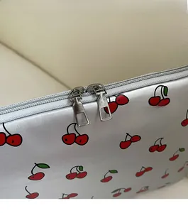 Detail of dual metal zippers on silver handbag with red cherry print pattern