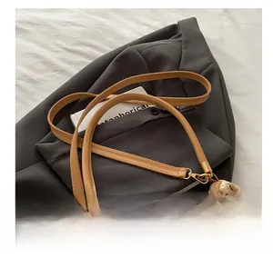 Detail of adjustable leather strap and woven texture of the beige dumpling bag