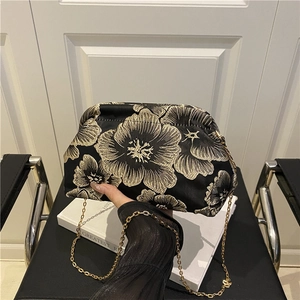 Elegant black cloud bag with gold floral embroidery and metallic chain shoulder strap