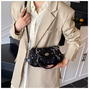 Détail du sac bandoulière noir avec motifs de nœuds blancs et chaîne en métal chic