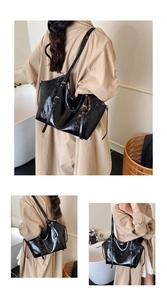 Close-up of black glossy patent leather tote bag featuring modern adjustable metal buckles