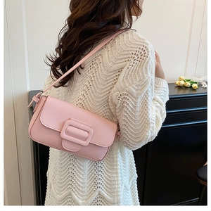 Side view of woman wearing a pale pink baguette bag with decorative large buckle