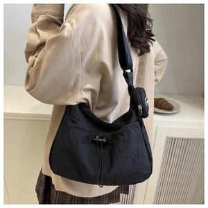 Detail of black nylon crossbody bag featuring a drawstring design and round coin purse