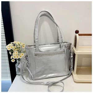 Détail d'un sac fourre-tout argenté avec poche avant en PVC et bandoulière amovible