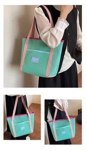 Detail of green mesh beach tote featuring pink straps and front pocket for storage