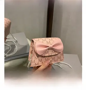 Detail of pink bow handbag with pearl chain and monogram print in mirror view