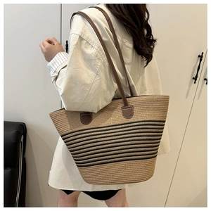 Détail du sac cabas en paille tissée avec rayures noires et anses en cuir marron
