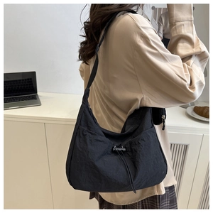 Detail of a black nylon hobo bag with drawstring and adjustable strap on a female model