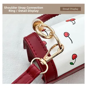Macro view of gold metal hardware and red stitching on a white cherry pattern handbag