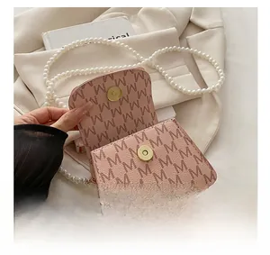 Detail of pink trapezoid handbag featuring M-letter pattern and pearl shoulder strap
