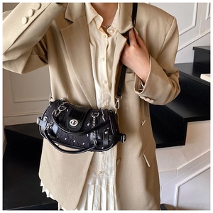 Détail d'un sac bandoulière noir en toile et cuir avec fermoir argenté et chaîne