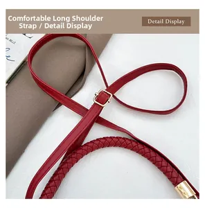 Detail view of adjustable long strap and braided handle on dark red crossbody bag