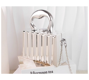 Detail of silver metallic clutch with vertical pleated texture and thick round handle