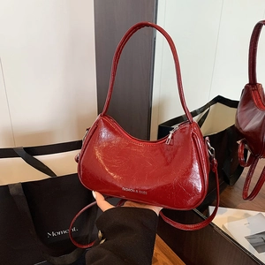 Deep red patent leather hobo bag with silver lettering and adjustable shoulder strap
