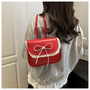 Red balletcore mini bag with lace trim and bow detail worn as a crossbody on grey hoodie
