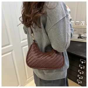 Dettaglio della borsa hobo intrecciata marrone scuro con cerniera dorata e texture minimalista