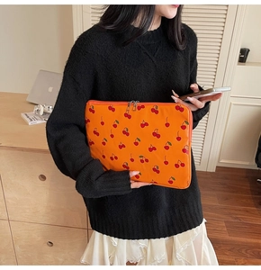 Detail of orange cherry print laptop sleeve with secure dual zippers and protective padding