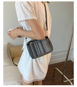 Détail du sac bandoulière tissé avec garnitures dorées et motif texturé élégant