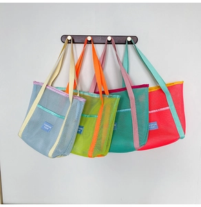 Detailed view of four colorful mesh beach tote bags hanging on hooks with vibrant contrast colors