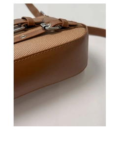 Detail of vintage brown saddle bag showing woven fabric texture and silver buckle