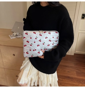 Silver cherry print laptop sleeve with dual zipper shown in a cozy office setting