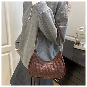 Détail du sac croissant tressé marron foncé avec fermoirs dorés et anse ronde