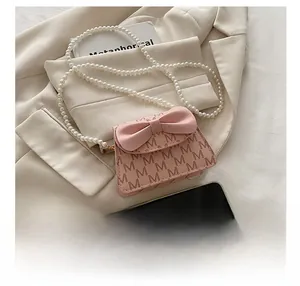 Detailed shot of pink mini crossbody bag with bow decoration and pearl bead strap