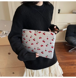 Detail of grey laptop sleeve with red cherry prints and dual metal zippers