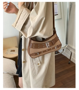 Detail of vintage brown patchwork underarm bag with buckle straps and eyelets on a model