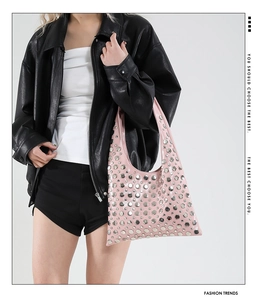 Detail view of pink patent leather bucket bag with silver metal rivets and fashion handle