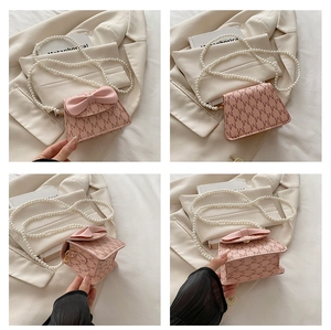 Pink mini handbag with M-pattern, decorative bow, and white pearl chain strap details