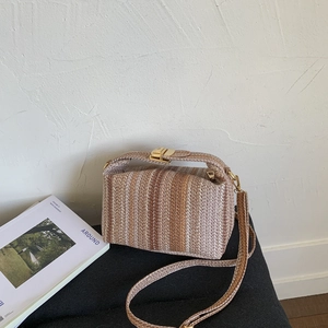 Détail du sac à main tissé à rayures avec fermoir doré et bandoulière réglable