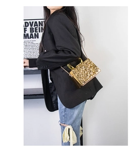 Detailed view of the gold acrylic evening bag with embossed texture and chain strap