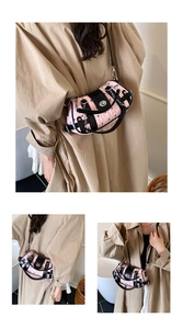 Détail du sac cylindrique rose avec imprimé nœuds noirs et chaîne décorative en métal