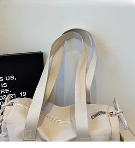 Close-up of beige canvas tote bag showing durable shoulder straps and drawstring detail