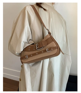Detail of vintage canvas underarm bag with decorative metal eyelets and buckled straps