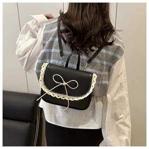 Detail of black ballet style bag with white lace trim and bow on model back view