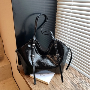 Glossy black wrinkled leather tote bag for women with dual straps on a wooden table