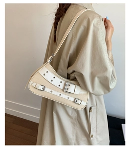 Detail of canvas underarm bag with silver metal eyelets and white leather straps