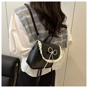 Detail of black faux leather backpack with white lace edges and a delicate ribbon bow