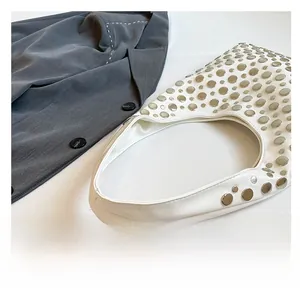 Detail view of white crescent bucket bag featuring silver rivet studs and a wide strap