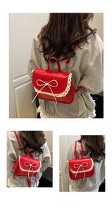 Dettaglio della borsa in pelle rossa con bordo in pizzo bianco e fiocco decorativo