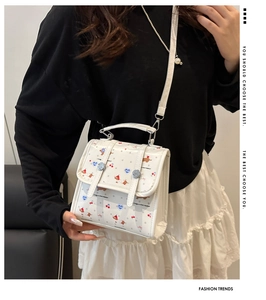 Nahaufnahme einer weißen gemusterten Umhängetasche an einem Modell in Mode