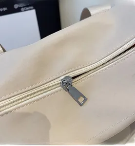 Detail of silver metal zipper and smooth stitching on cream canvas tote bag