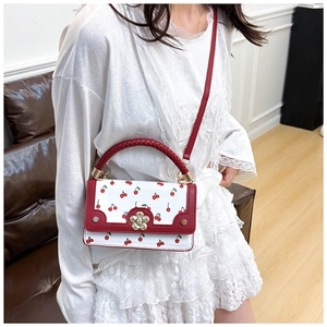 Detailed shot of cherry print handbag with floral buckle on white lace dress