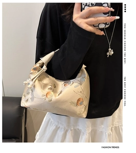 Detailed close-up of beige silk handbag with elegant flower and bird embroidery patterns