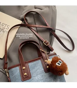 Detail of adjustable shoulder strap on denim contrast bucket bag with plush charm