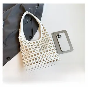 Detail view of a white bucket bag with silver stud accents and integrated handle design
