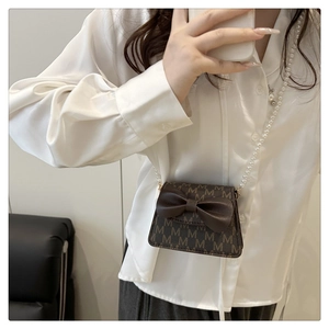 Detail of mini crossbody bag with leather bow and pearl chain strap for girls